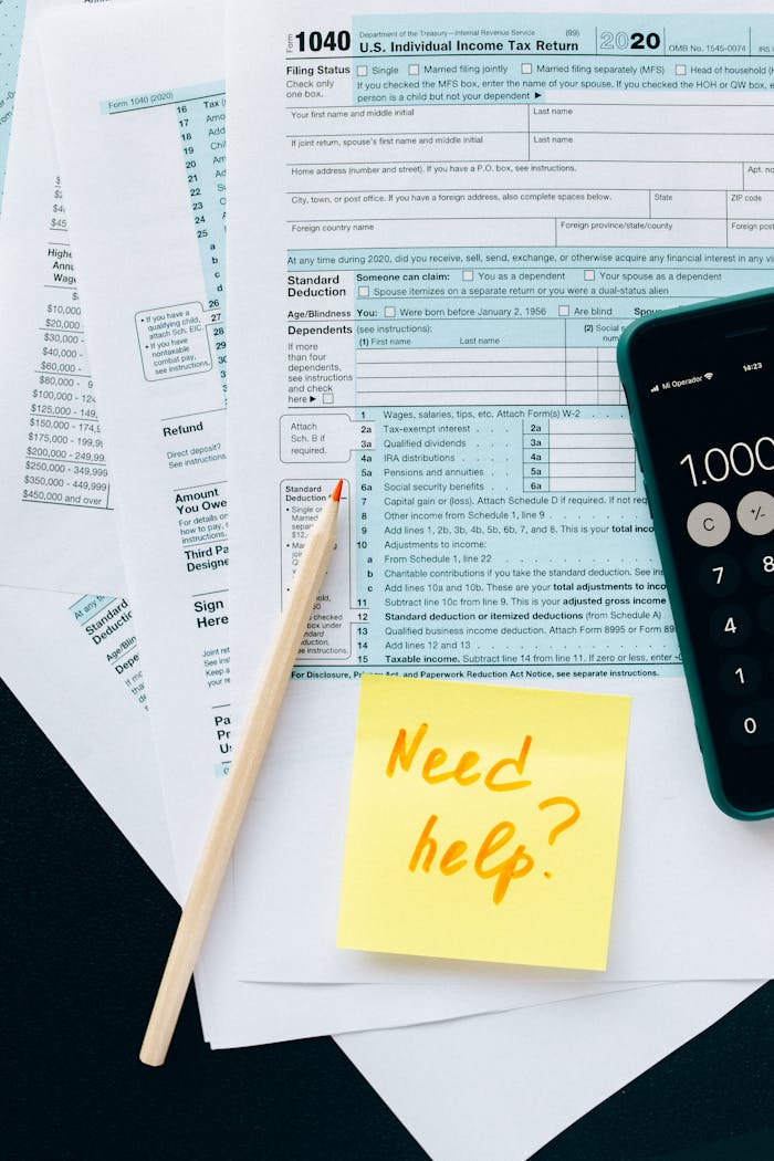 Services-01 Close-up of tax forms with a calculator and a note asking for assistance.