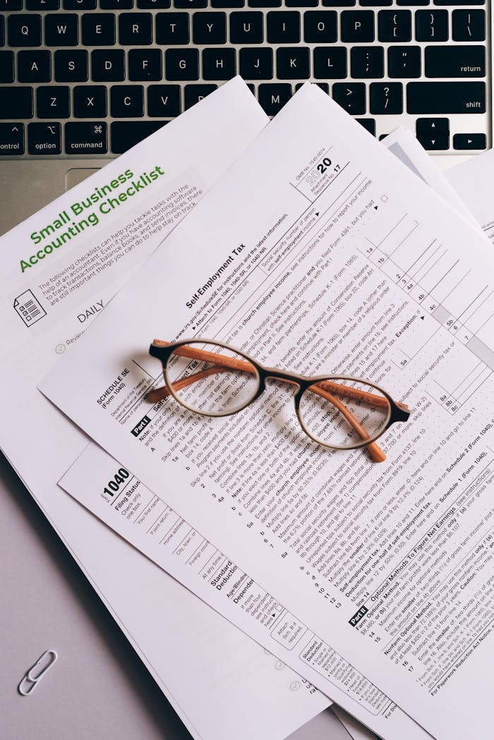 Services-03 Overhead view of tax documents and eyeglasses on a laptop keyboard, ideal for finance or accounting themes.